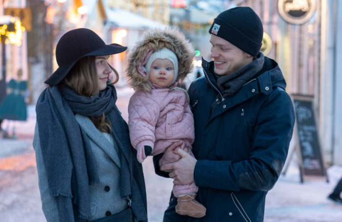 A happy family of three standing outside on the street in wintertime