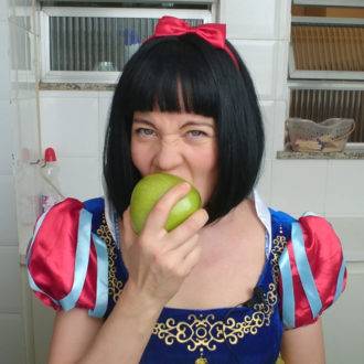 Artist Ninni Korkalo, dressed as Snow White, bites into a green apple.