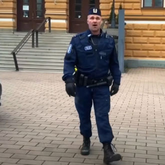Police officer Petrus Schroderus, in full uniform, sings beside a police car in front of City Hall in the Finnish city of Oulu.