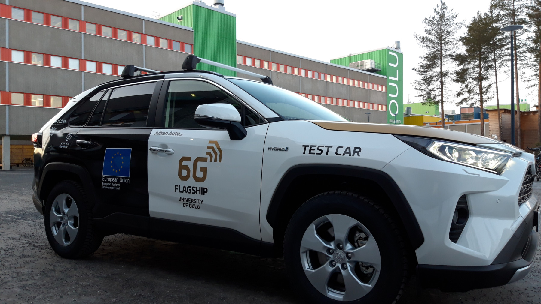 A car with the words 6G Flagship and Test Car on its side is parked outside a building at the University of Oulu.
