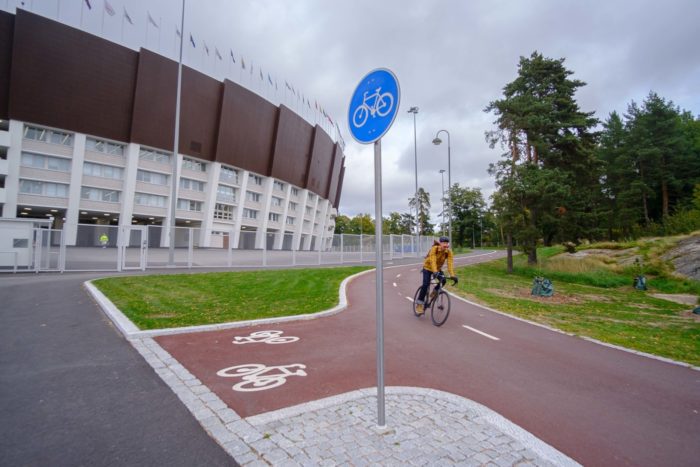 A biker cycles past a stadium on a smooth, new bike path.