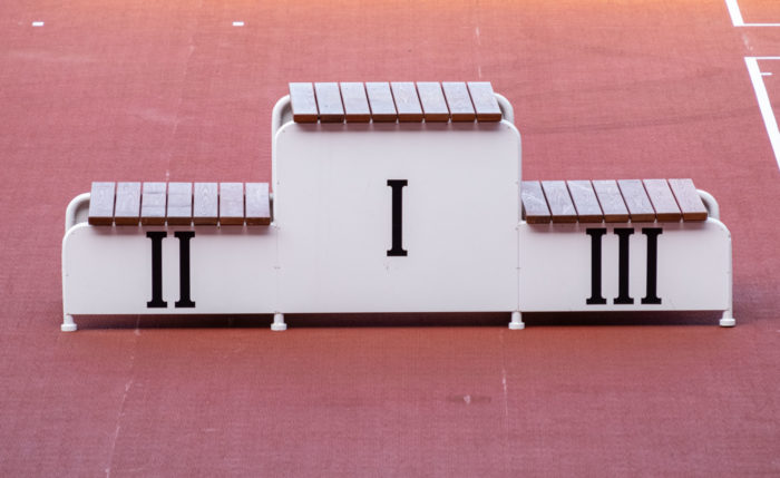 A podium with steps for three winners stands on part of a running track.