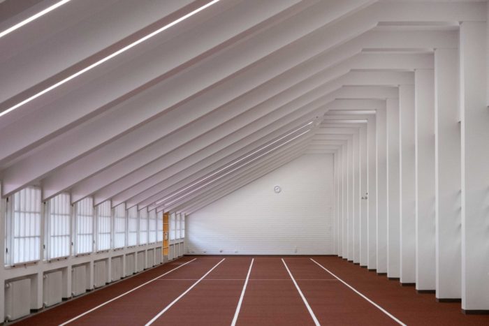 On voit un bout de piste d’athlétisme en salle en ligne droite.