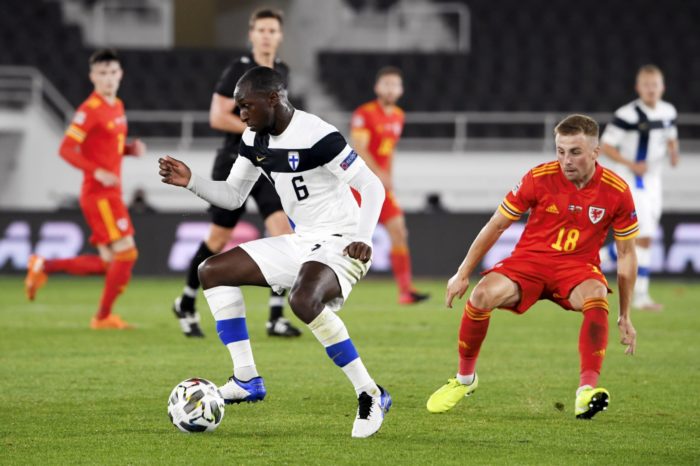 In a men’s international football match, a player controls the ball while an opposing player attempts to cover him.