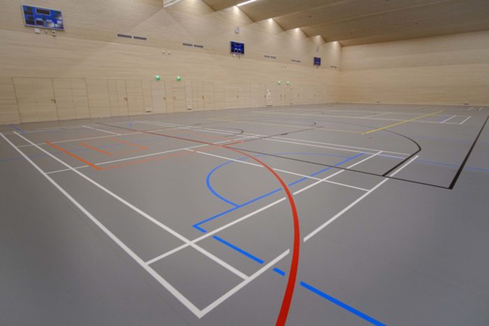 A gymnasium floor shows lines of various colours for various sports.