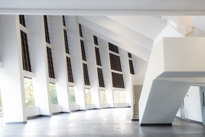 Un large hall intérieur est bordé d’un côté par deux escaliers menant à l’étage supérieur.