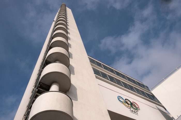 A thin tower rises up against a blue sky.