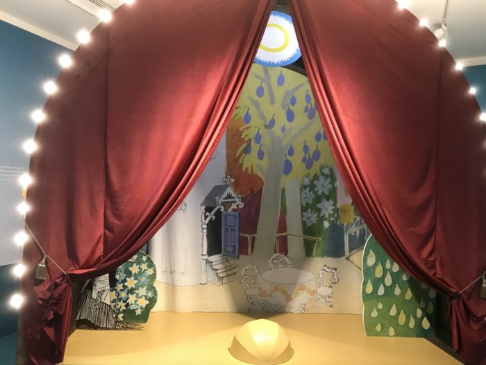 Curtains and lights flank a small stage.