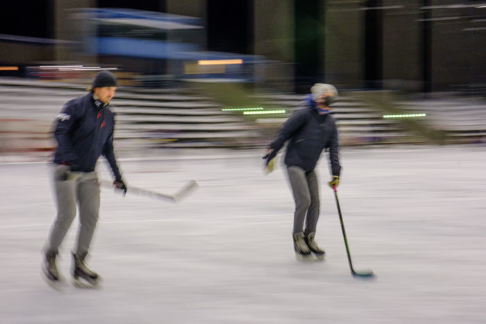 Deux joueurs de hockey sur glace évoluent sur une patinoire extérieure.