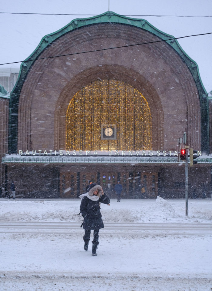 Une personne traverse une rue face à un bâtiment public alors qu’une tempête de neige fait rage.