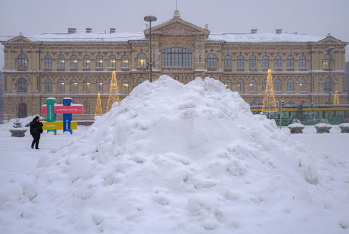 A stately museum building is partially visible behind an enormous pile of snow.