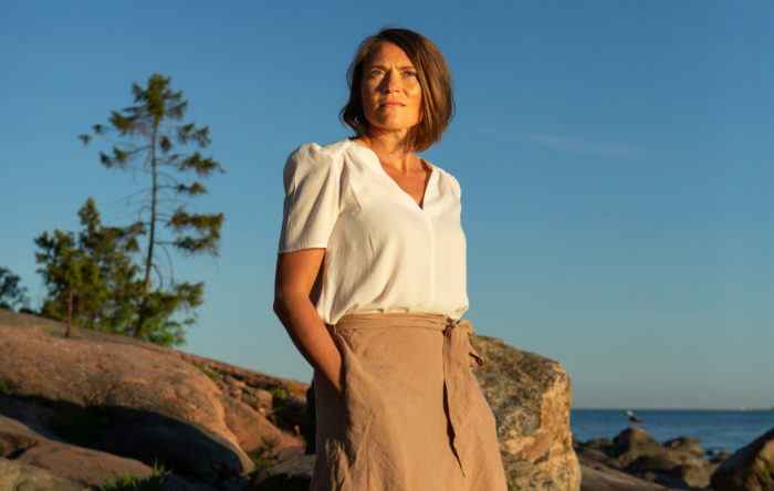 Uma mulher está de pé em frente a um litoral rochoso.