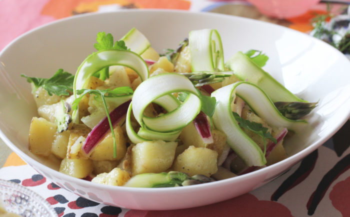 Uma tigela de salada de batata com batatas, cebolas e aspargos.