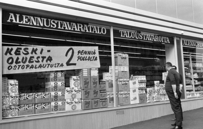 Two people look at goods in a store window.