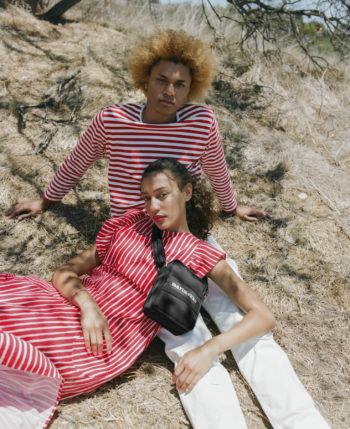 Two people dressed in striped clothes sit under a tree.