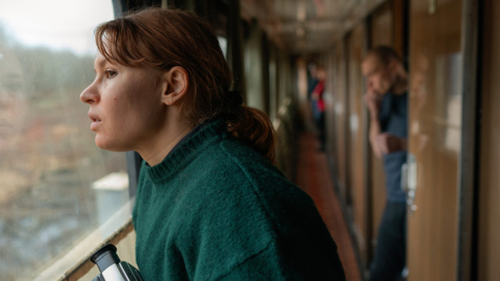 Женщина смотрит в окно поезда.