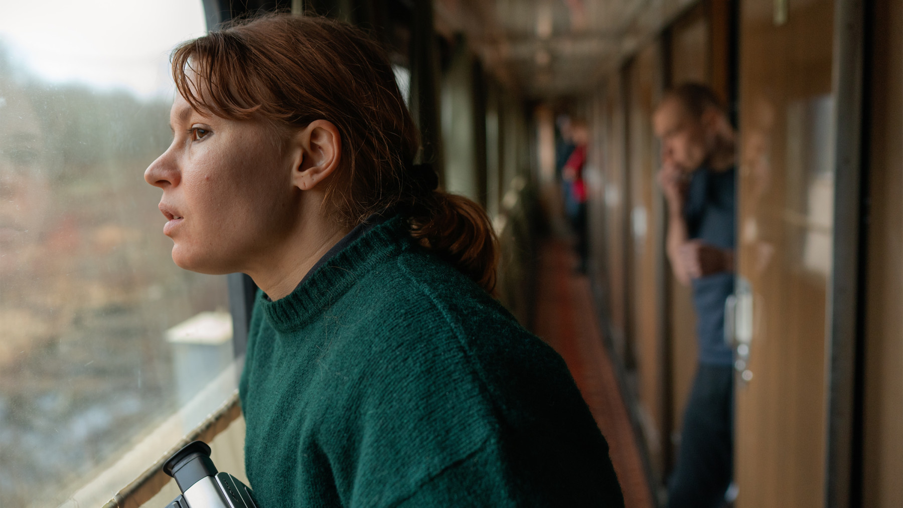 Une femme nez contre la vitre d’un train regarde les paysages qui défilent.