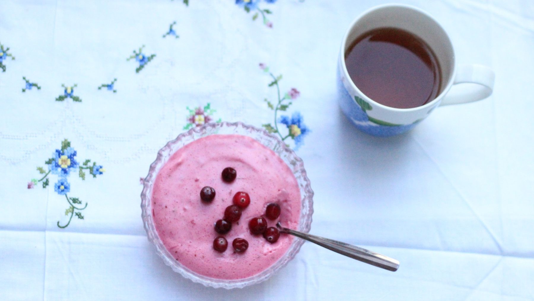 Un cuenco de gachas rosadas de sémola con bayas y una taza de té.