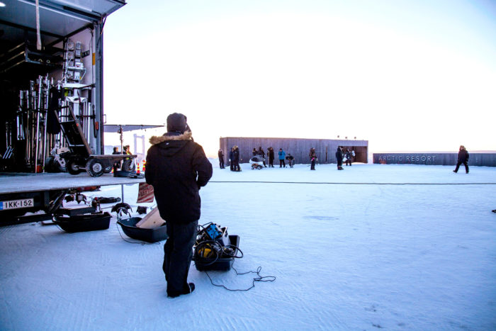 Ein Mann steht neben einem Lastwagen, von dem Filmausrüstung auf den verschneiten Boden heruntergeladen wird.