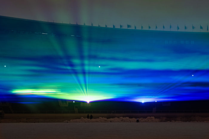 Um padrão ondulado que lembra os roxos e amarelos da aurora boreal emerge das lâmpadas do Estádio Olímpico.