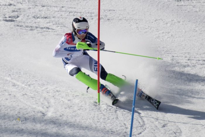 A slalom skier cuts a curve on his way past a gate.