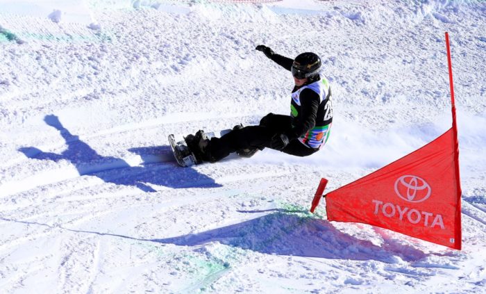 Um snowboarder passa por uma bandeira.