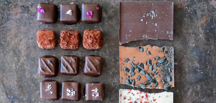 Fileiras de chocolates diferentes, incluindo pequenas trufas e pedaços de barras de chocolate.