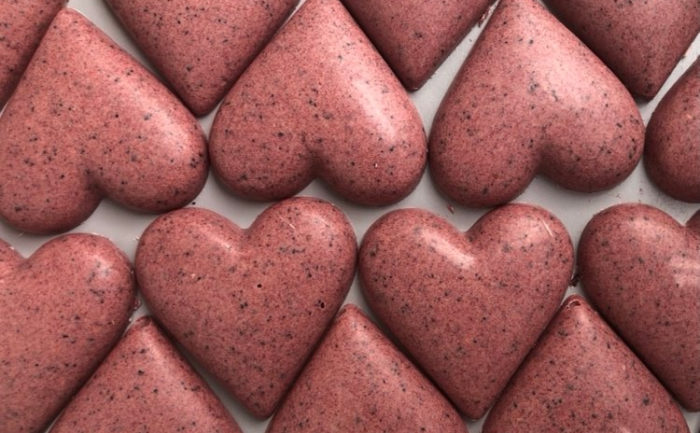 On voit plusieurs rangées de chocolats roses en forme de cœur.