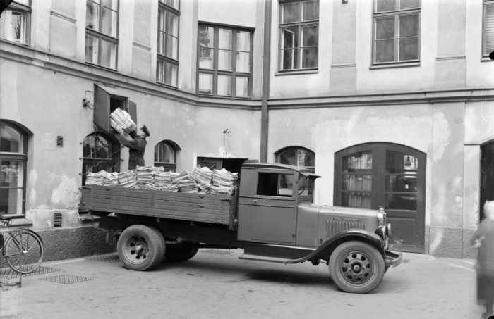 一名工人将成捆的报纸堆放在一辆卡车的后面。
