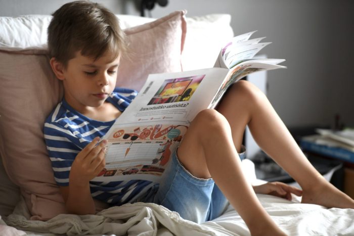 Un enfant est en train de lire un journal.