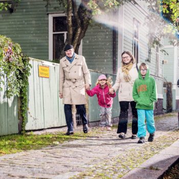 Une famille comptant deux jeunes enfants passe à pied devant une maison en bois.