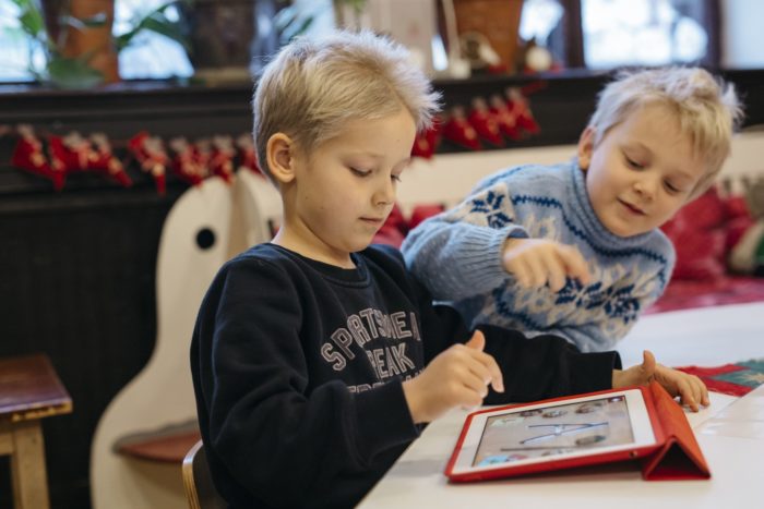 In a school setting, two young kids are using a tablet computer.