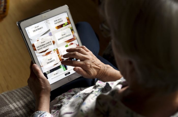 Eine Person, die im Rentenalter oder älter zu sein scheint, scrollt auf einem Tablet.
