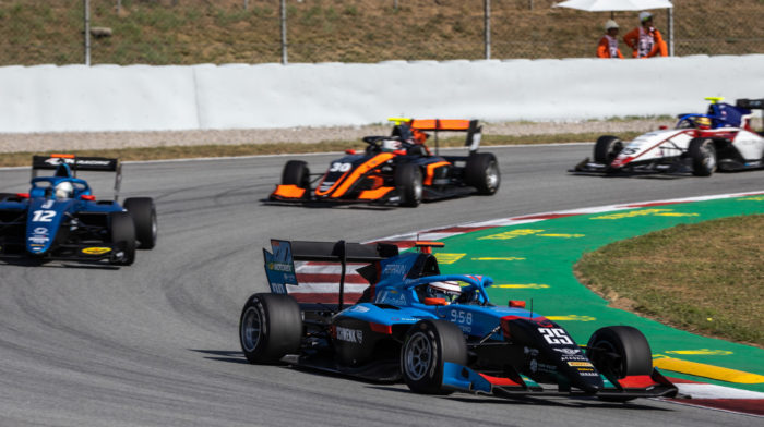 Tres coches de F3 dando la curva en un circuito de carreras.