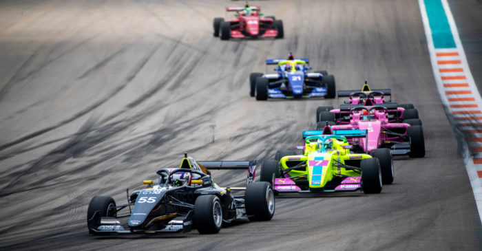 Cinco coches de carreras entran en una de las curvas de un circuito.