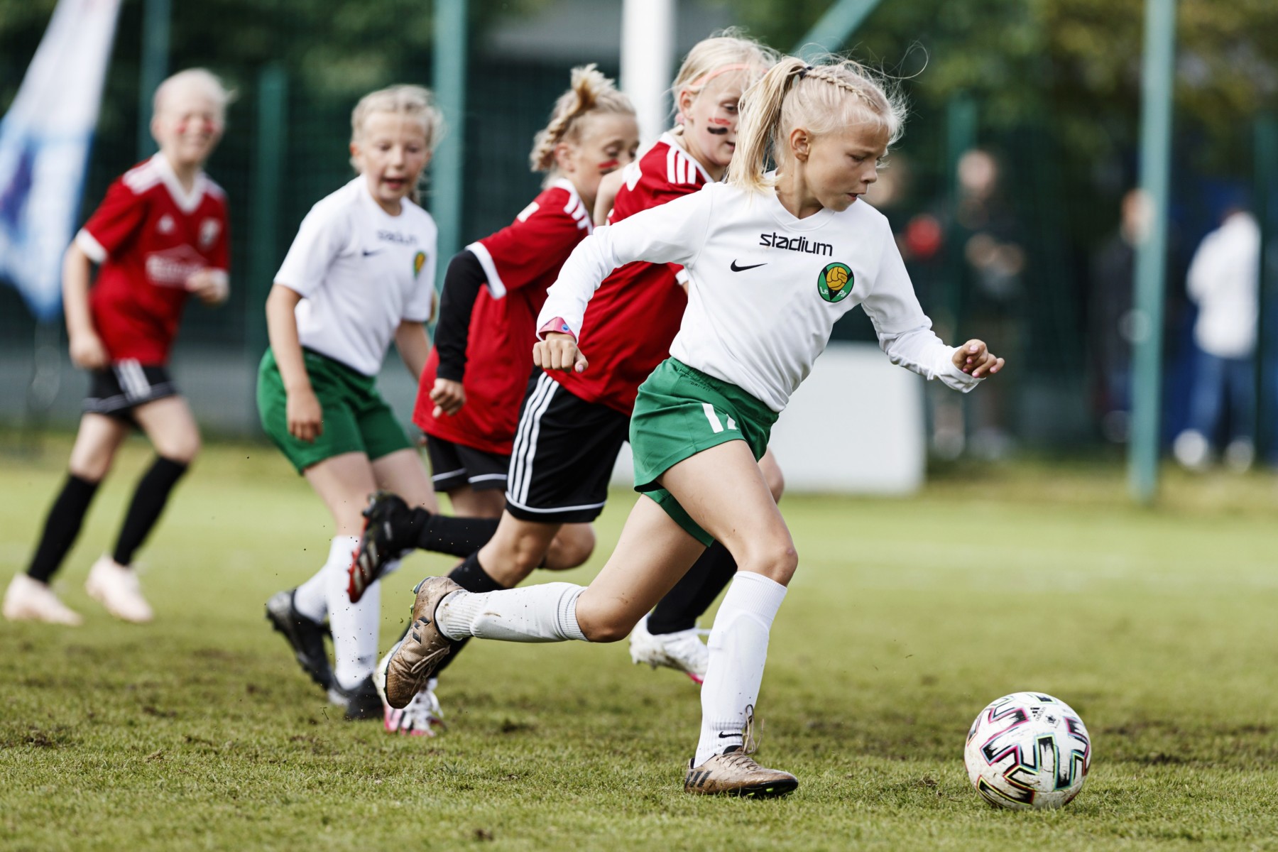 Una jugadora de fútbol sobrepasa a otras chicas regateándoles el balón.