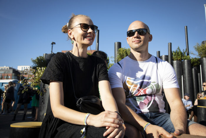 A woman and a man smile, both wearing sunglasses.