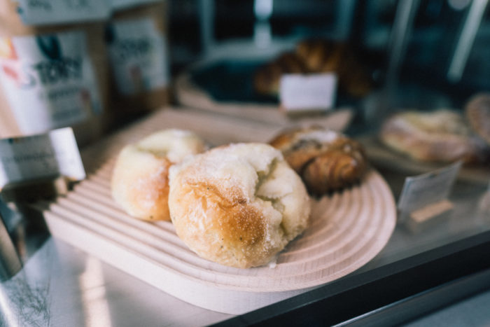 Sobre el mostrador de una cafetería hay una bandeja con bollos cubiertos de azúcar.