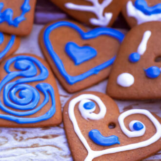 A pile of heart-shaped gingerbread cookies decorated with blue and white frosting.
