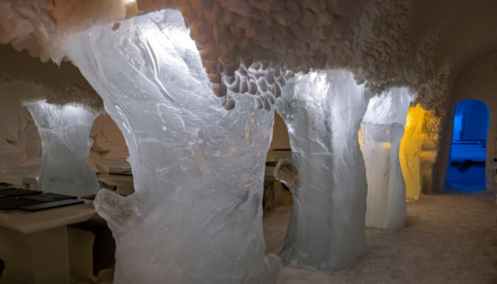 Several tree sculptures made of ice stand beside tables in a restaurant.