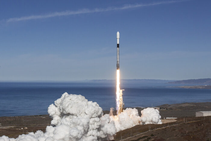 Un cohete es lanzado hacia un cielo despejado, dejando una gran nube de humo a ras del suelo.