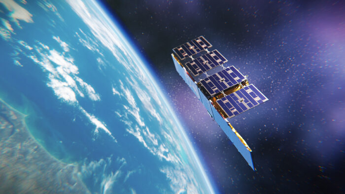 A satellite made of several flat metal panels is in space above planet Earth.