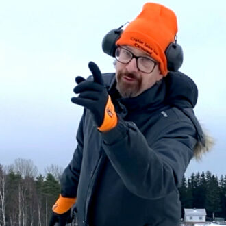 一名男子身穿厚重的冬季服装，微笑着手指前方。