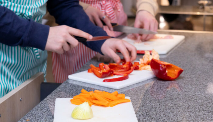 Os alunos estão cortando ingredientes em tábuas de corte.