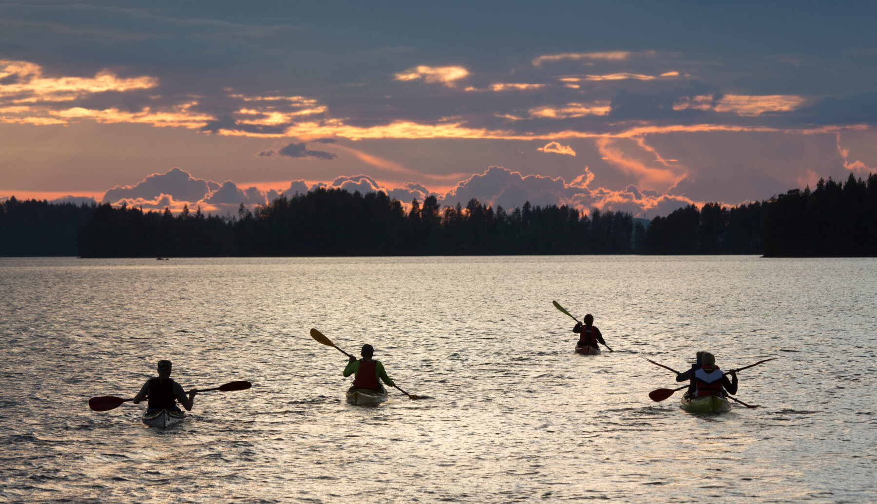 A kayaker paddling across a peaceful Finnish lake surrounded by forest, symbolising the calm journey of navigating a new career at Marshalls