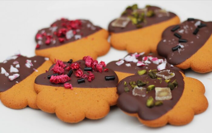 Several chocolate-dipped gingerbread cookies lie on a white background.