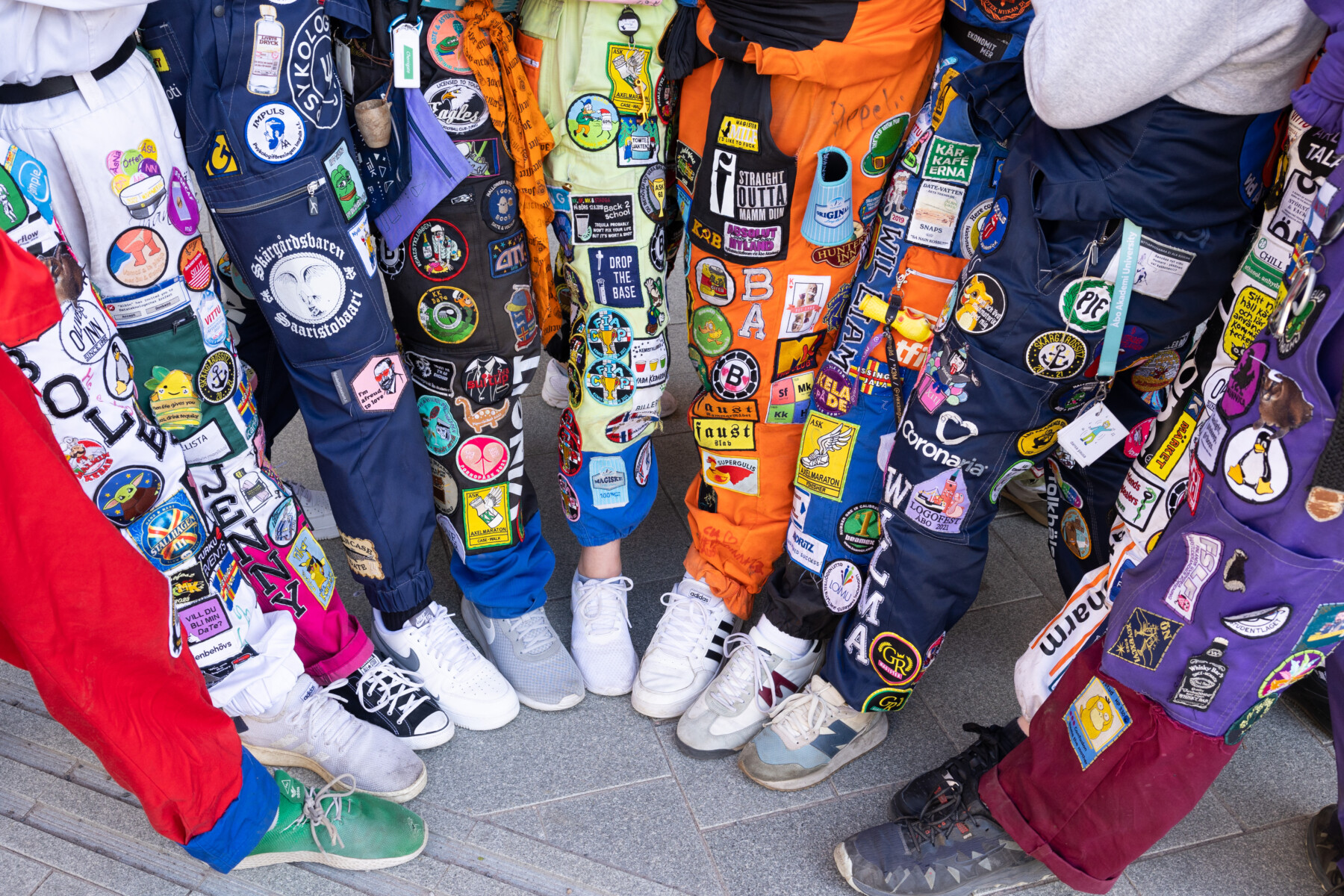 Once hombres y mujeres jóvenes vestidos con monos de colores posan formando un apretado semicírculo, cada uno de ellos con una pierna extendida hacia el centro de este.