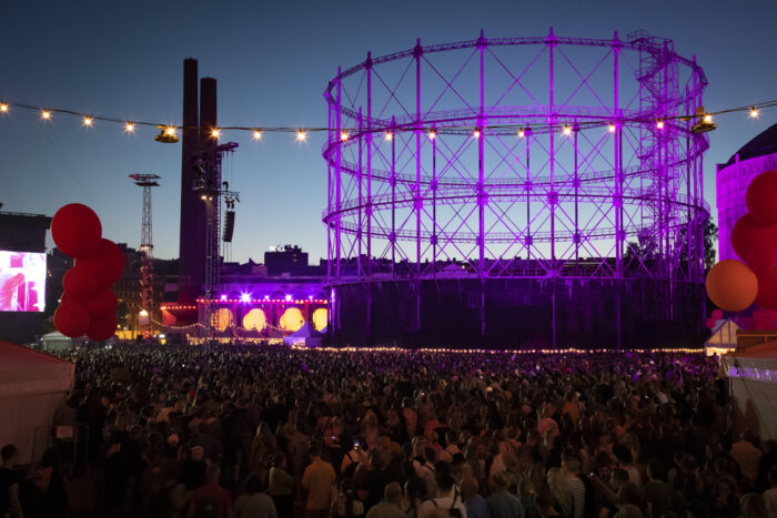 Tras la multitud de asistentes a un concierto, los edificios aparecen cubiertos de luces ornamentales.