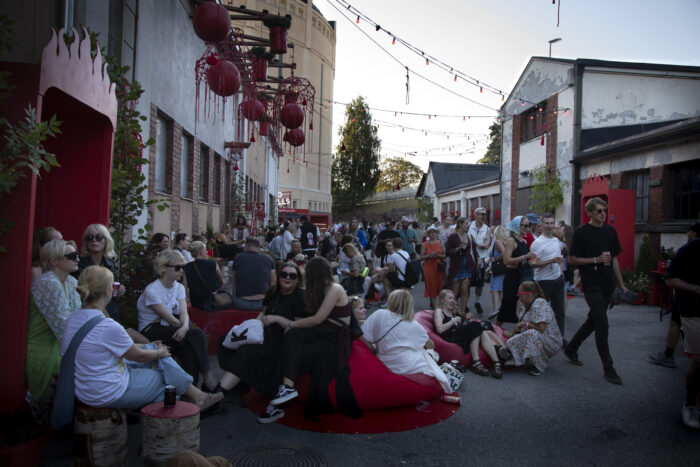 Under strings of decorative lights, people are sitting in groups or strolling along.