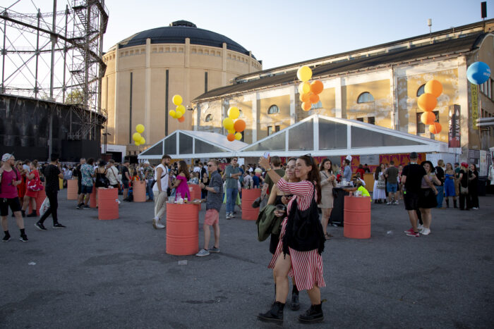 Des personnes circulant sur le site du festival passent devant un bâtiment industriel d’aspect ancien.